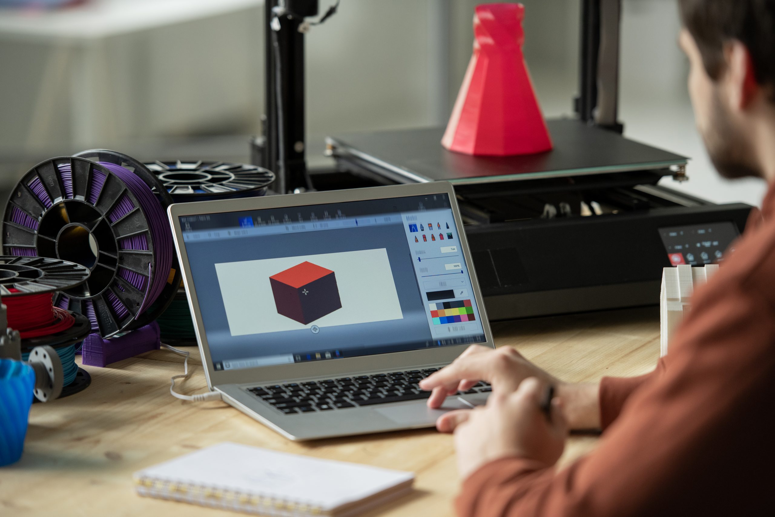 Creative designer working over new 3d model on laptop screen before printing it on special equipment in office