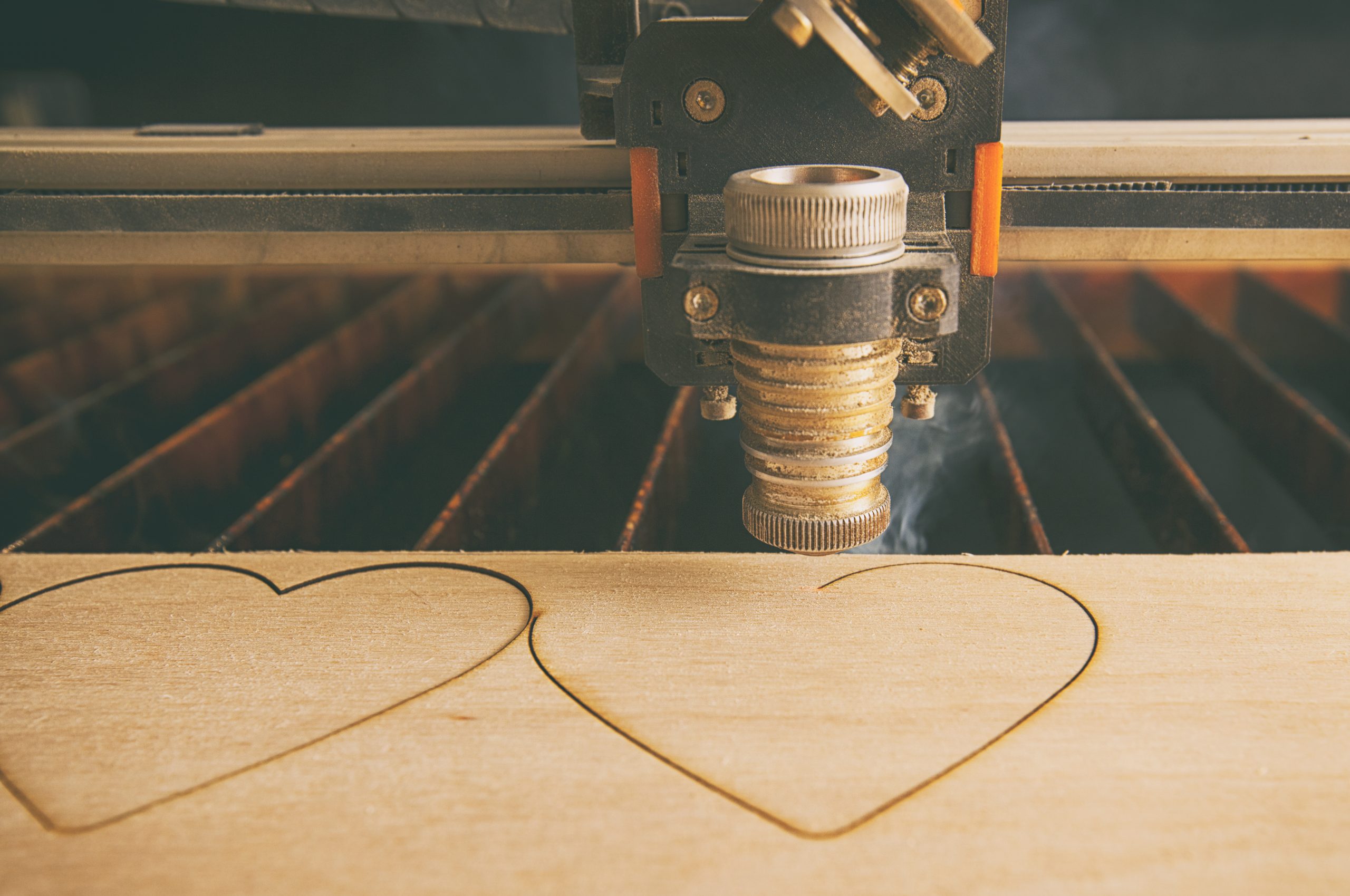 Laser cutting machine is cutting hearts in the wooden plank